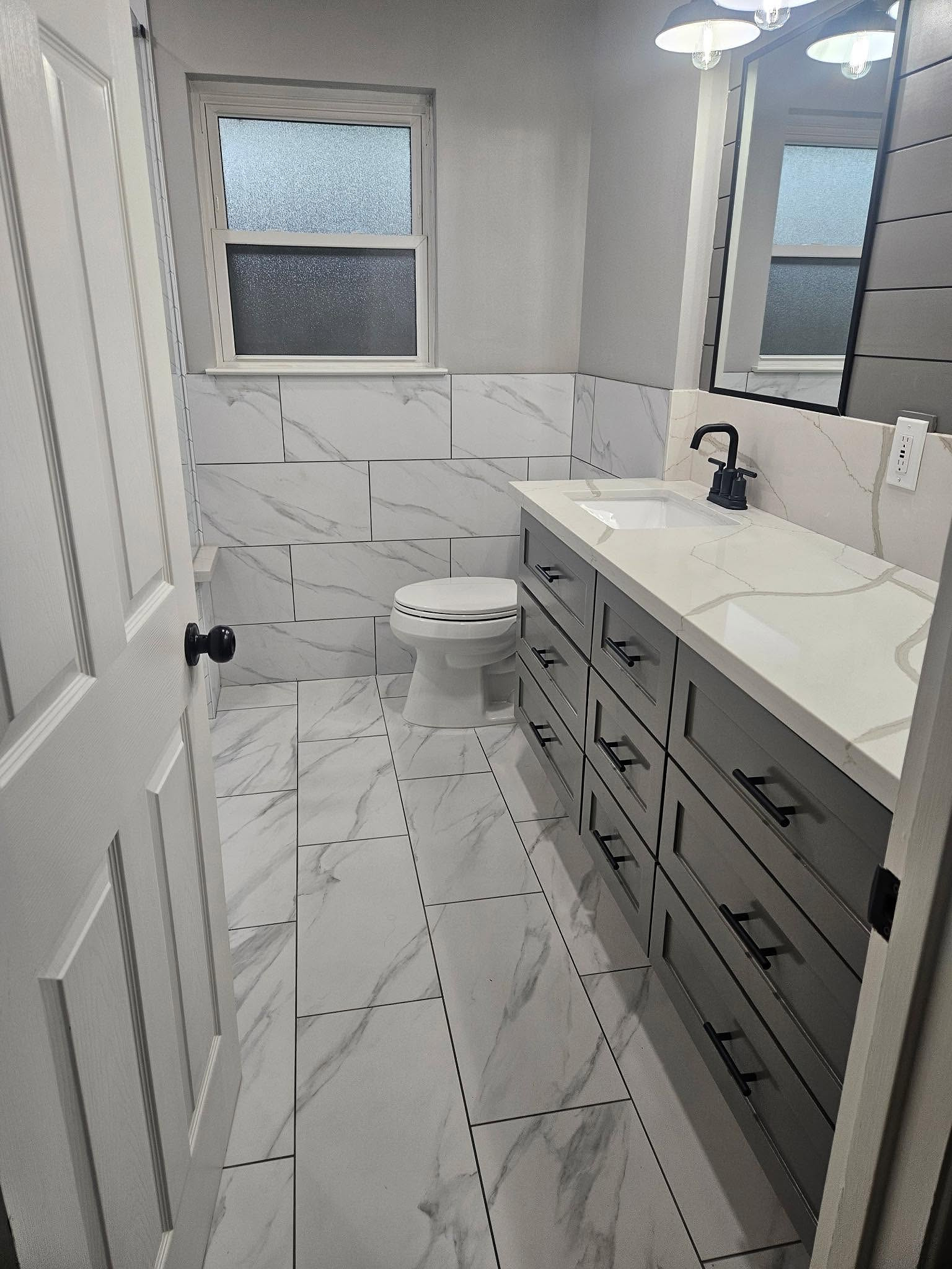 The same hall bath finished in marble-look porcelain with a grey vanity by Reeder
