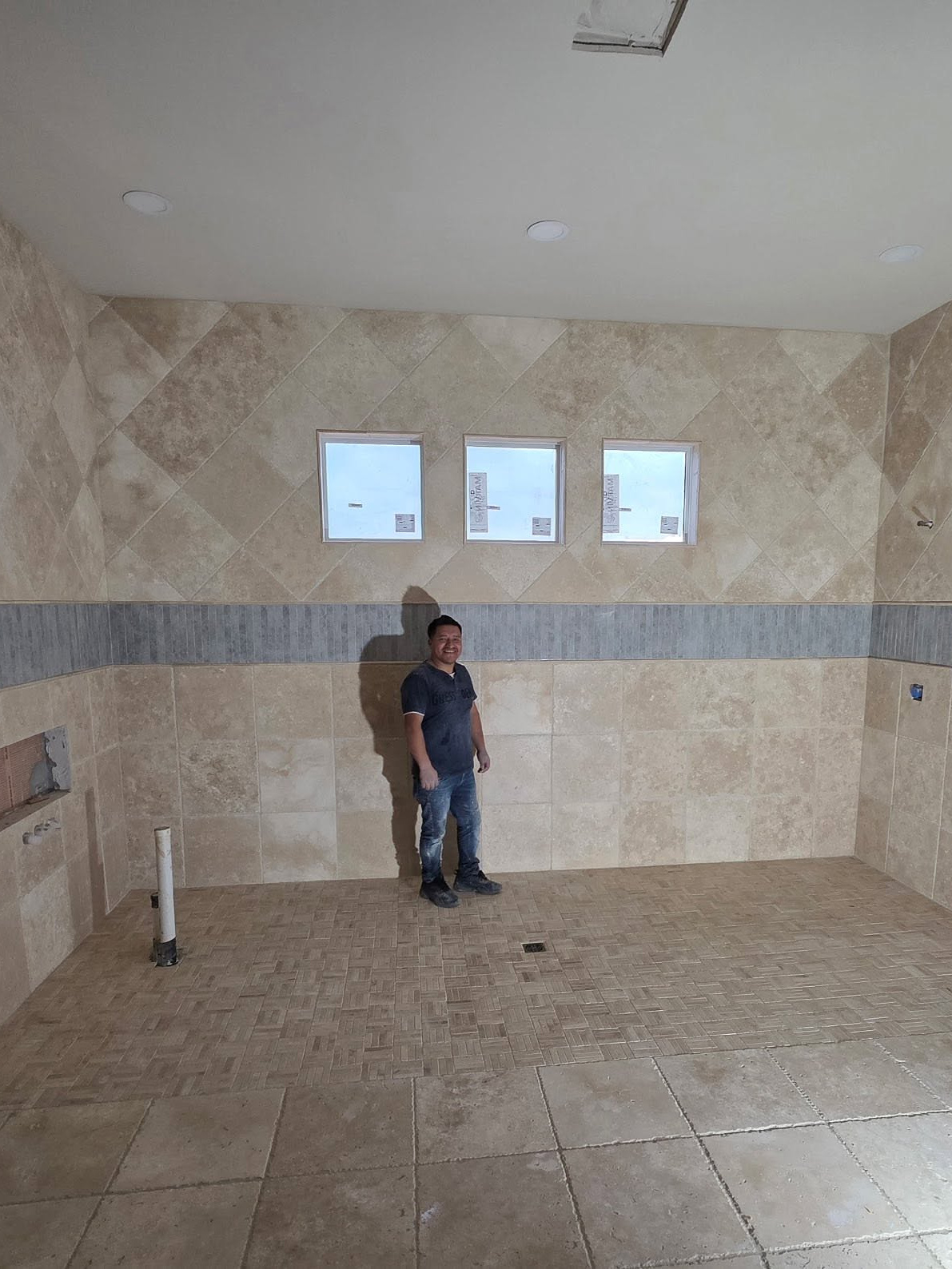 The same primary bath finished in travertine tile by Reeder