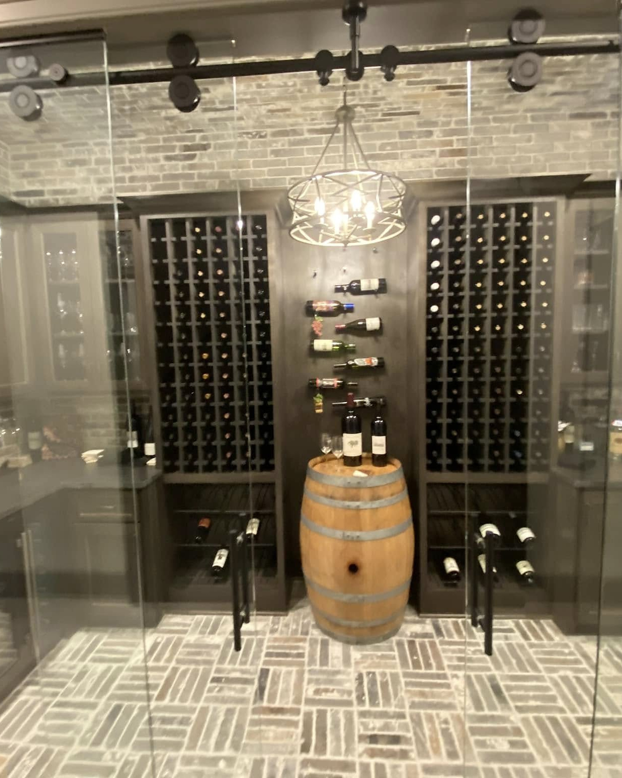 Custom brick and glass wine cellar with herringbone floor built by Reeder