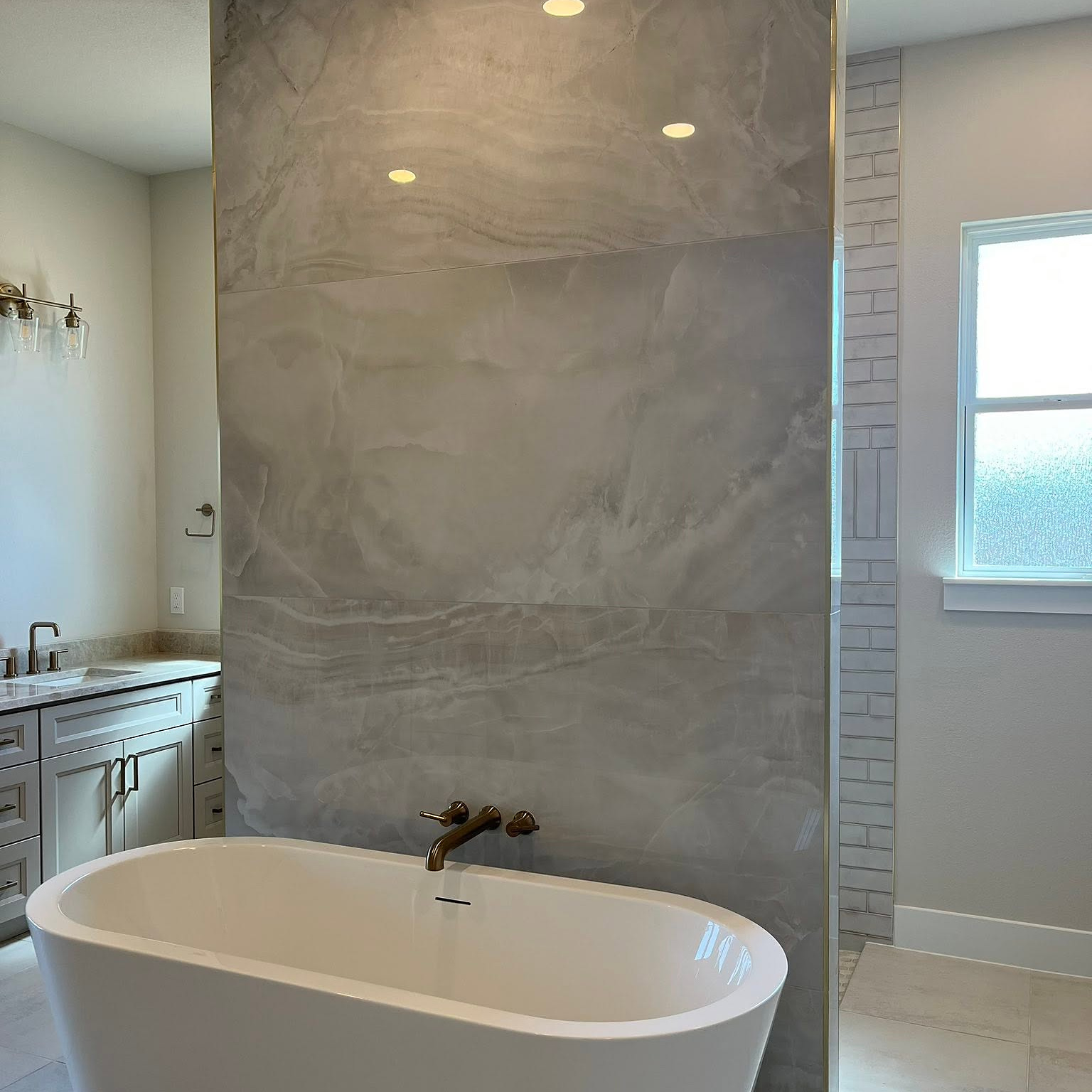 Onyx-look slab feature wall behind a freestanding tub by Reeder