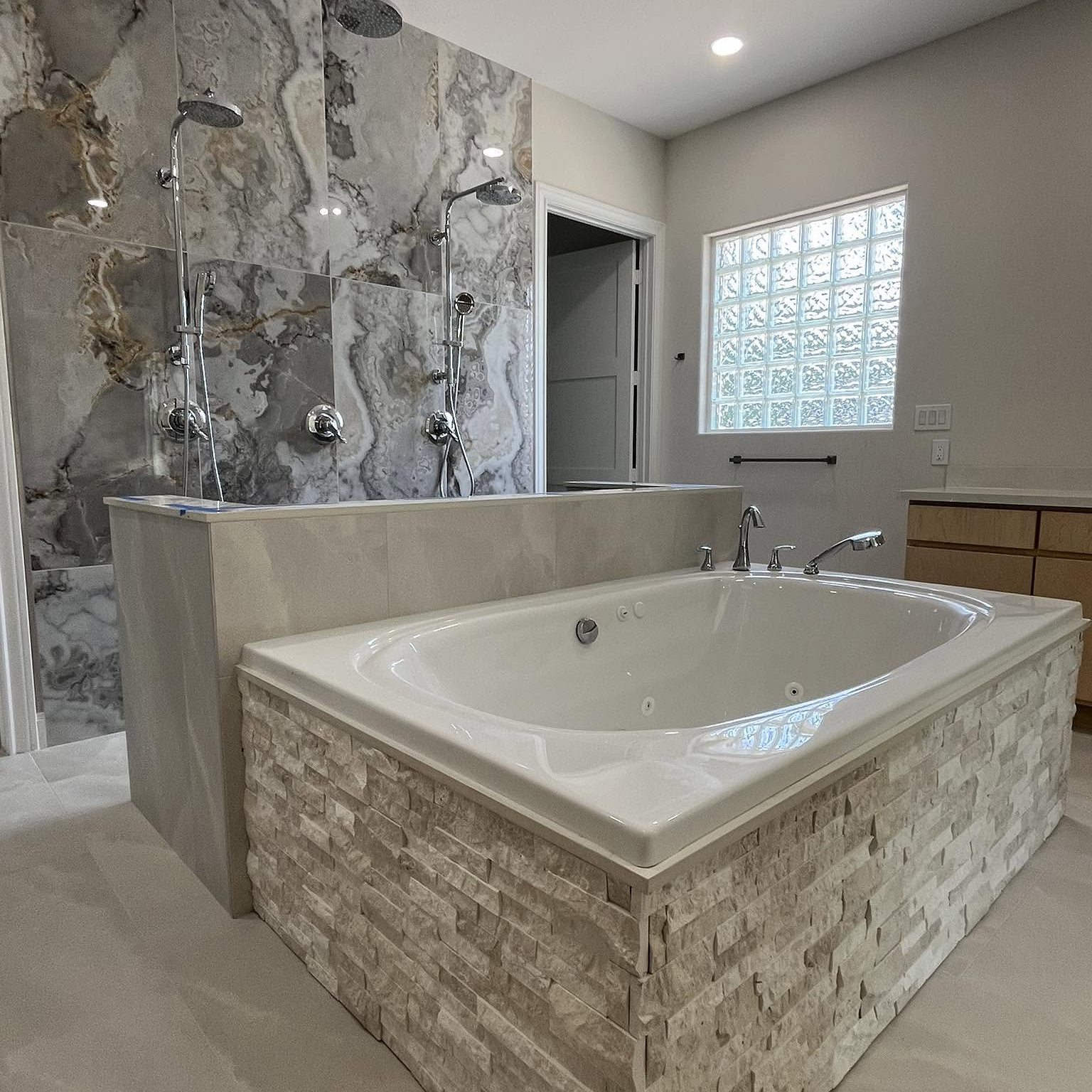 Natural-stone tub surround and marble slab dual shower by Reeder
