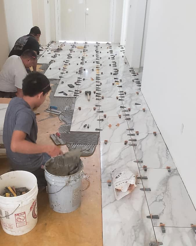 Reeder crew setting a large-format tile floor in a Houston entry
